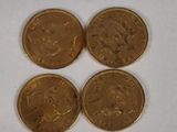 four gold coins sitting on top of each other on a white surface