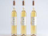 three bottles of white wine sitting next to each other on a white surface