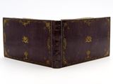 un vieux livre relié en cuir, orné de motifs dorés, posé sur une surface blanche