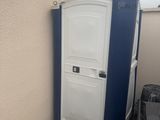 des toilettes portables blanches et bleues à côté d'une poubelle