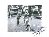 a black and white photo of a boy and a dog on a swing