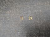an old black book with gold letters on it sitting on top of a table