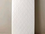 un matelas blanc posé sur une table en bois près d'un mur