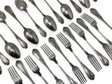 a lot of silver spoons and forks on a white surface