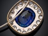 a close up of a blue sapphire and diamond pendant on a silver chain