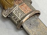 a silver and gold knife with a wooden handle