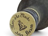 a wine bottle with a bell on top of it