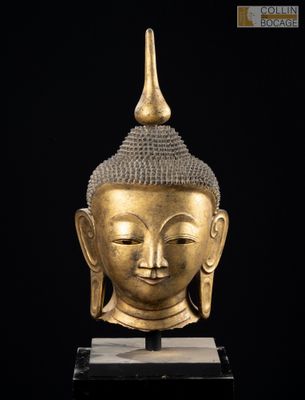 une tête de Bouddha en or posée sur un socle en marbre