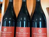 trois bouteilles de vin rouge sont posées sur une étagère dans un magasin
