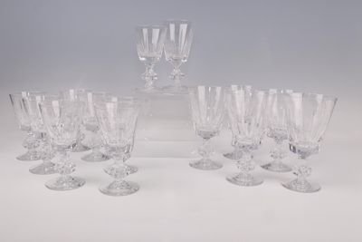 six verres à vin en cristal et une carafe posés sur un plan de travail blanc