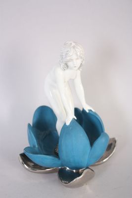 une figurine posée sur une fleur bleue