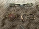 two rings, a tie bar, and two other items on a table