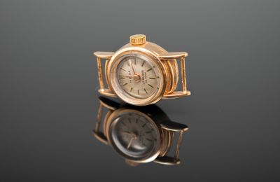 une montre-bracelet en or posée sur une surface noire