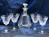 four wine glasses and a decanter on a table