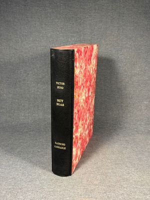 an old book sitting on top of a table next to a black book