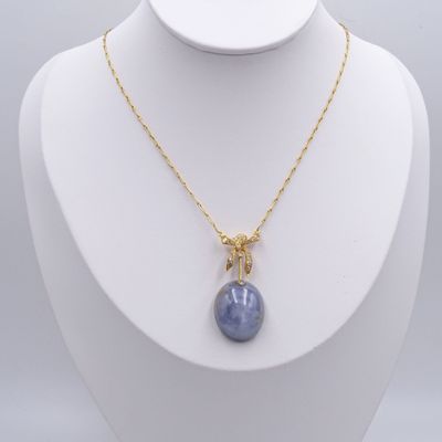 un collier plaqué or avec un pendentif en pierre bleue sur un mannequin