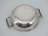 a silver plate with a handle on it on a table