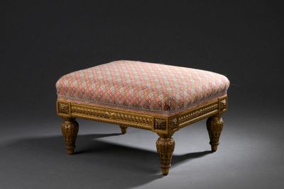 un repose-pieds rembourré dont l'assise est recouverte d'un tissu à motifs