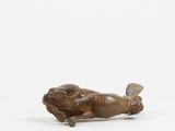 bronze statue of a dog lying on its back on a white surface