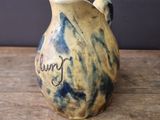 a brown and blue vase sitting on a wooden table