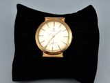une montre en or posée sur un coussin noir, sur une table