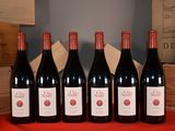 six bottles of red wine are lined up on a table