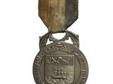 une vieille médaille en argent sur fond blanc, ornée d'un ruban noir et or