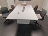 une grande table blanche entourée de chaises dans une pièce