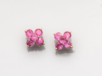 une paire de boucles d'oreilles en saphir rose posées sur une surface blanche