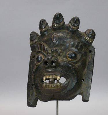 une image représentant un masque en bronze posé sur un socle métallique