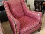 a red chair sitting in a living room next to a fireplace