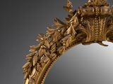 a mirror that has a gold frame with leaves and flowers on it