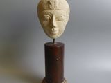 sculpture représentant une tête de femme, posée sur un socle en bois
