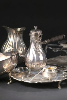 un plateau en argent avec une carafe en argent et un plateau en argent sur lequel sont disposés des couverts en argent