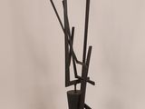 a tall black vase with sticks sticking out of it
