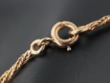 a close up of a gold chain with a clasp on a black surface
