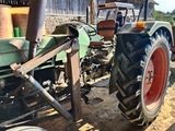 un tracteur garé sur la terre battue près d'un bâtiment