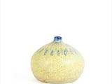 a yellow and blue vase sitting on a white surface