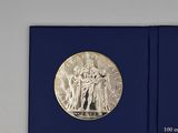 an image of a silver coin in a blue box on a white surface