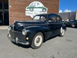 an old black car parked in front of a building