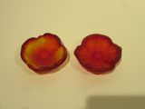 une paire de bols en verre en forme de fleurs rouges et jaunes posés sur un support blanc