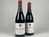 two bottles of red wine sitting next to each other on a table