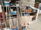a pile of brooms and other tools in a garage