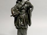 une statue représentant un homme avec une guitare, posée sur un socle