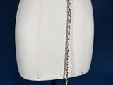 a white mannequin with a chain and a pink flower on it