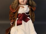 a doll that is sitting on the ground wearing a hat