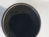 a black cup sitting on a white counter top