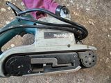 une ponceuse filaire posée par terre à côté d'une paire de chaussures