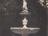 une statue au sommet d'une fontaine, au milieu d'un parc