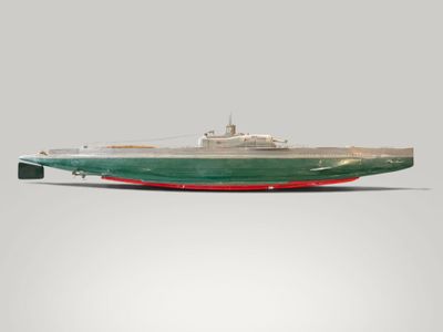 a model of a green and red boat on a white surface